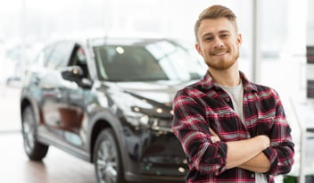 Man standing smiling in front of car