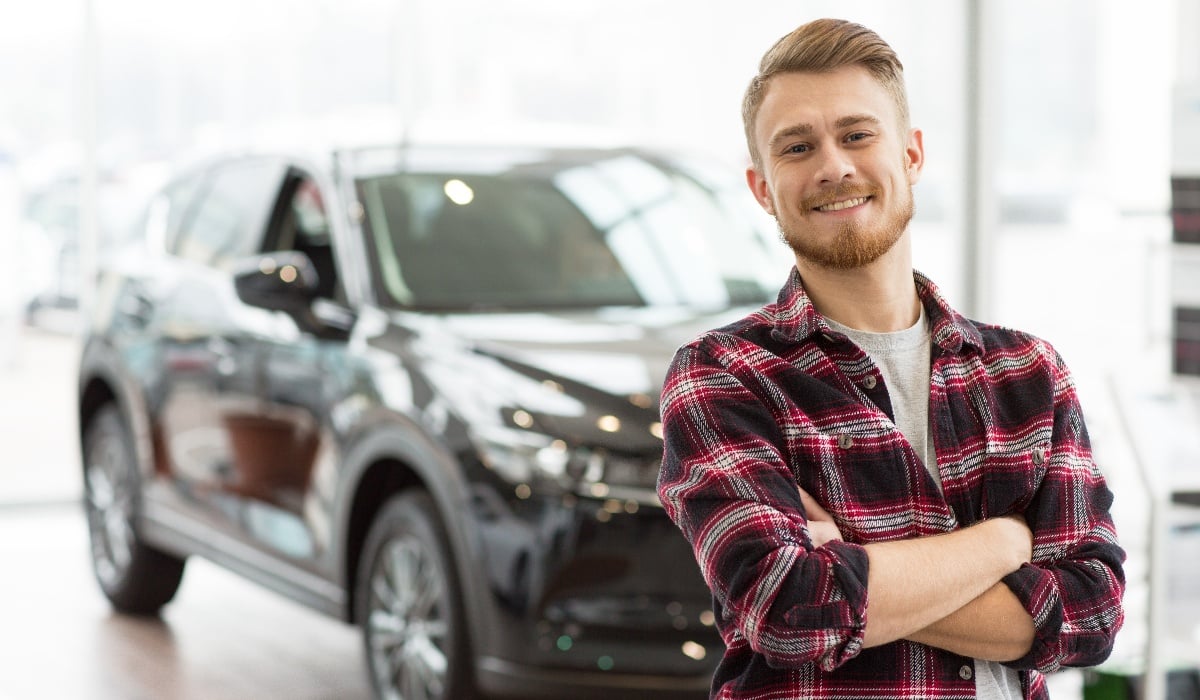 Man standing smiling in front of car